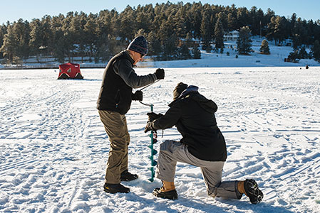 Two men using an auger during ice fishing on Evergreen Lake