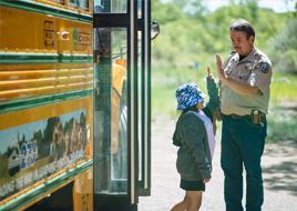 Image of a CPW ranger giving a young girl a high five in front of a bus.