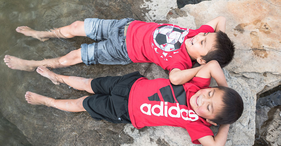 Two young boys lay with their legs in a stream at Mancos State Park