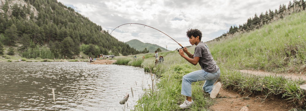 A young man reels in a fish at Kriley Pond in Golden Gate Canyon State Park.