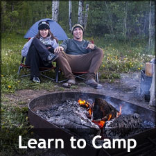 A couple camping near a small campfire