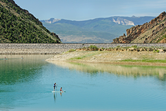 Two people on a paddleboard with view of lake and hills
