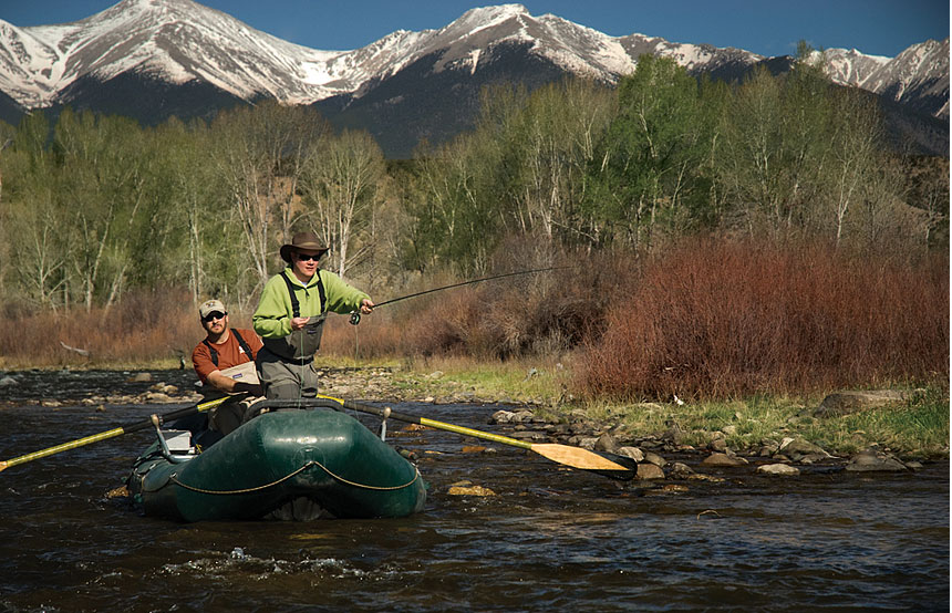 Two men river rafting and fly fishing.