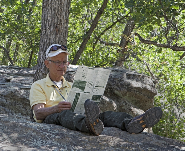 Older man lounging on rock reading park brochure