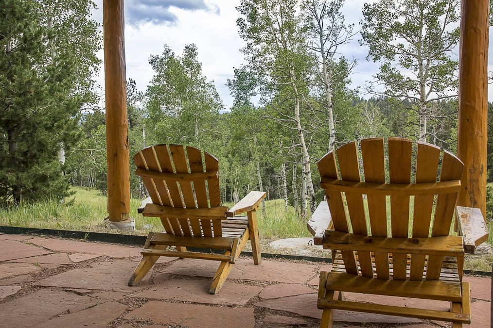 2 adirondack chairs on the deck of a cabin