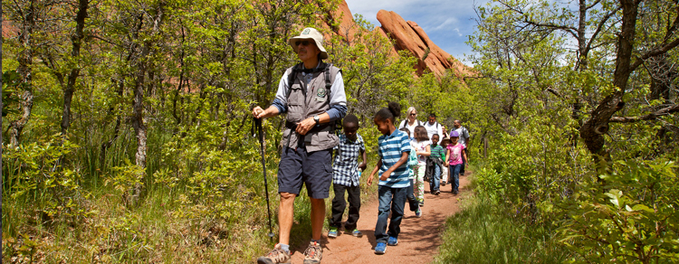Roxborough volunteer leads a group of school age children on a hike through Roxborough State Park.