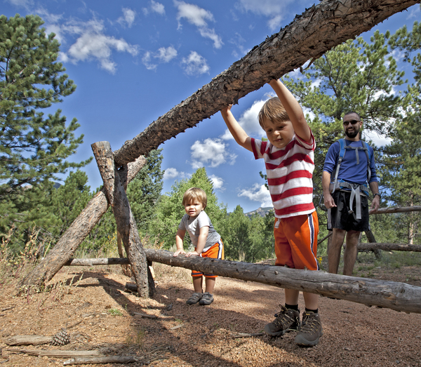 kids playing on fence while hiking a trail with Dad