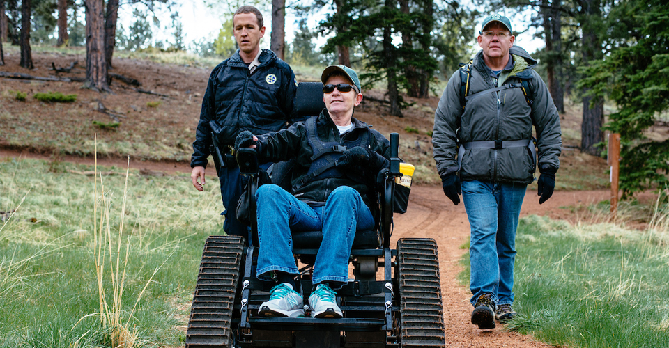 Volunteers accompany person in trackchair.