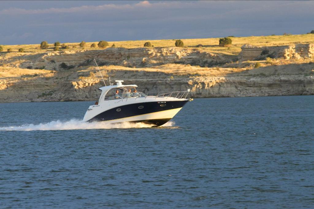 A power boat cruises left to right across Lake Pueblo State Park at sunset