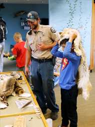 An interpreter at Barr Lake State Park shows a child animal furs, feathers, and turtle shells.