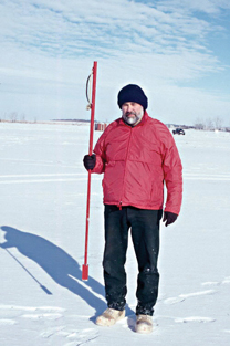 A fisherman stands with an ice chisel. Photo credit North Dakota Game & Fish Dept.