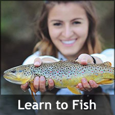 Young woman smiling and holding up the fish she caught