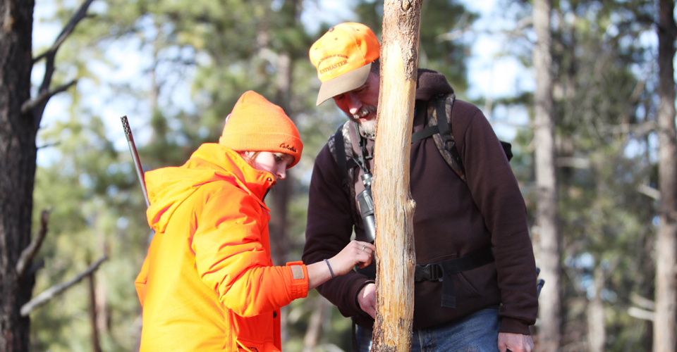 A mentor teaches a youth hunter about tracking.