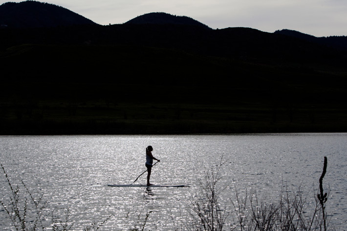 black and white image of woman on paddleboard with hills in background