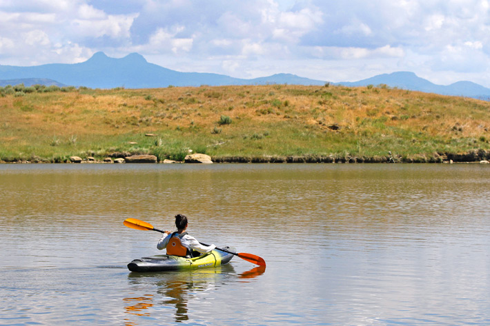 woman kayaking with mountain backdrop